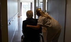 Rear view of female nurse with senior man sitting in wheelchair at an aged care home