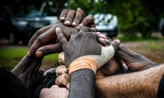 The Tiwi Bombers huddle during the quarter-time break against the Crocs. The white hand of Ashton Hams pokes into the pile, front left. Tiwi Bombers football team in Darwin.