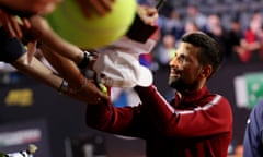 Novak Djokovic signs autographs for fans shortly before being struck by a metal bottle.