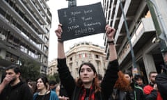 A demonstrator holds a placard saying: 'One year after ... 57 souls are seeking justice' during a rally in Athens.