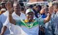 Jacob Zuma raises both hands among a crowd of people.