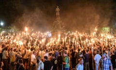 White men throng around a statue while holding lit torches.