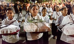 School children carrying symbols of Christ crucifixion, including a crown of thorns, chains and nails, lead a procession through the streets of Larantuka. 