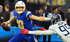 Los Angeles Chargers quarterback Justin Herbert (10) stiff arms Tennessee Titans linebacker Rashad Weaver (99) during the fourth quarter at SoFi Stadium.