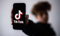 Person holds out smartphone with TikTok logo