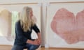 Branigan crouching down and looking away from the camera, at one of two large heart-shaped tree trunk prints behind her