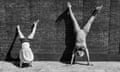 A young girl and a man doing handstands against a wall