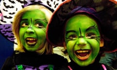 Two children with green faces, looking delighted in their Halloween costumes