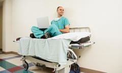 Doctor sitting on gurney with laptop