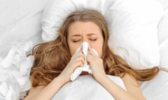 Woman blowing nose in bed