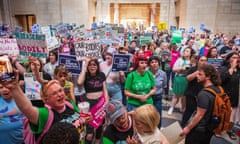 A large group of people hold signs reading messages like 'Our Bodies Our Choice' inside a government building