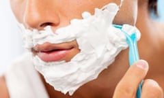 a person shaves their face with blue razor and white shaving cream