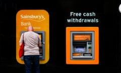 A man withdraws cash from an ATM, Brighton. 