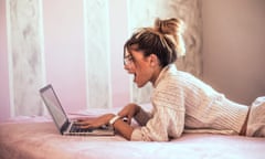 A young woman lying on bed using laptop (Posed by a model.)