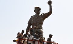 TOPSHOT-BURKINA-POLITICS-MEMORY-HISTORY<br>TOPSHOT - Residents pose under the bronze statue of Burkina Faso’s former President Thomas Sankara who was killed on October 15, 1987, on the sidelines of the inauguration of his memorial at the Conseil de l’Entente in Ouagadougou on March 2, 2019. (Photo by ISSOUF SANOGO / AFP)ISSOUF SANOGO/AFP/Getty Images