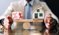 a man balances a % sign and a house