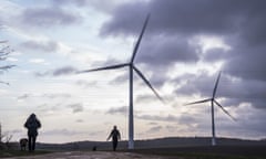 Two people walking their dogs at Hook Moor windfarm, near Leeds, with two wind turbines visible.