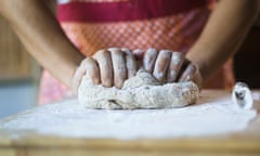 Mixed race woman kneading dough in kitchen