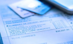 Credit Card On A Hospital Invoice<br>A hospital bill for $36,000 with a line item of various charges is photographed with a very shallow depth of field. A credit card and a mobile device rest out of focus in the background.