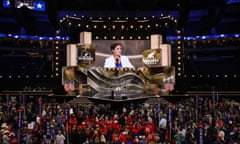 a woman's face is projected on a giant screen before a hall full of people