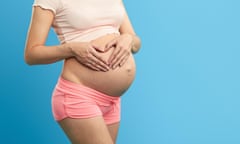 pregnant girl keeping her palms in the heart shape on her belly.