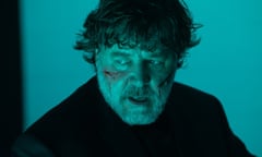 Film still of a man with cuts on his face looking off to the side in a room with blue lighting