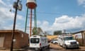 two white cars in front of buildings and a water tower