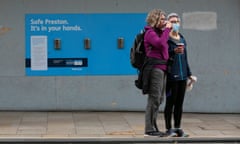 Women in masks by a hand sanitising station in Prestong