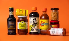 An assortment of condiments in jars and bottles against an orange background