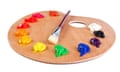 A wooden artist’s palette loaded with various coloured paints and a brush