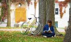 Girl reading book on university campus in fall with yellow bicycle; Kingston, Ontario, Canada<br>Girl reading book on university campus in fall with yellow bicycle