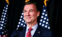 a man smiles in front of an American flag