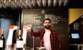Bearded man standing behind beer tap in bar