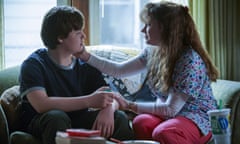 A boy and his mother sit on the couch as the mother comforts him