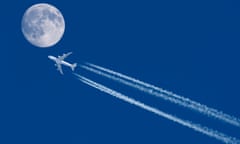A plane flying across a blue sky with the moon visible nearby