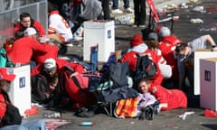 People wearing red bent down and laying down around paper trash cans