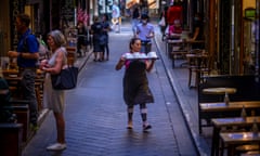 A worker carries dishes among cafes in Melbourne