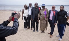 The politicians in suits pose with people in casual wear for a photo taken by someone standing mostly out of shot