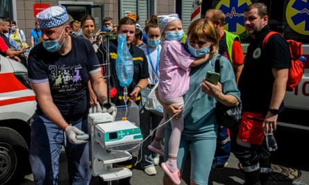 Medics carry a little girl and equipment at the site of a missile strike on the Okhmadyt children’s hospital in Kyiv, Ukraine