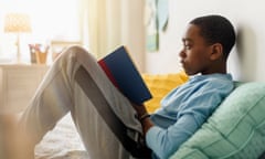 A boy reading a book on a bed