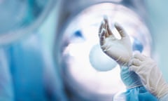 Surgeon adjusting glove in operating room<br>stock image of surgeon's gloved hand underneath operating theatre light