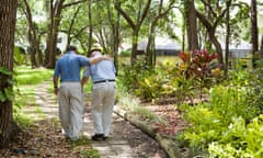 View from behind of an adult son walking with his senior father in the park.