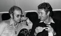 Tony King (centre) with Elton John and John Lennon, with plates of food and drinks, on a plane