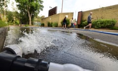 Residents on their morning walk past a hose emitting water as the South Pasadena High School swimming pool undergoes maintenance and repairs on May 16, 2015 in South Pasadena, California.  The pool must be emptied and in an effort to reuse as much water as possible - with the chlorine counteracted - the potable water, recommended for gardening only and not human consumption, is on offer to the public who bring their own containers to collect water. As California endures its fourth year of drought, some cities and water districts across the state have implemented restrictions on swimming pools, from moratoriums on swimming pool construction to restrctions on filling and draining pools. AFP PHOTO / FREDERIC J. BROWNFREDERIC J. BROWN/AFP/Getty Images