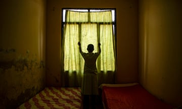 Young woman in silhouette against a curtained window