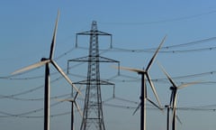 Wind turbines with a large pylon in the background against a blue sky