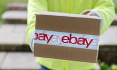 A courier delivering an eBay parcel to a customers front door. The cardboard box is wrapped in tape clearly showing the eBay logo.