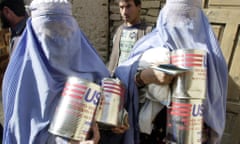 Two Afghan women carry cans of cooking oil provided by US Aid in Kabul on Wednesday, 21 November 2001