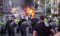 Riot police hold back protesters near a burning police vehicle after disorder broke out in Southport.