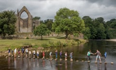group of kids crossing the river on stepping stones at Bolton Abbey.
